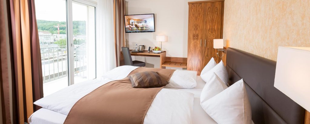 Komfortables Hotelzimmer im Hotel Amaris mit Doppelbett, Arbeitsplatz und Balkon mit Ausblick.