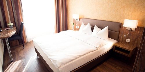 Modernes Standardzimmer im Hotel Amaris mit komfortablem Doppelbett und Sitzbereich.