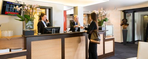 Moderne Hotelrezeption mit Holztheke und persönlichem Empfang.