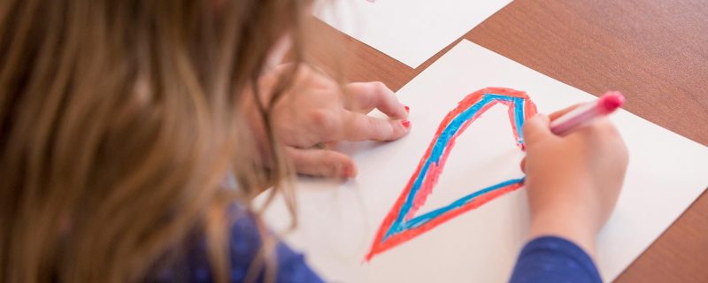 Kind malt ein Bild am Tisch im Familienzimmer des Hotel Amaris.