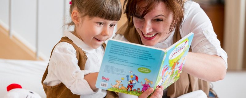 Mutter liest mit Kind ein Buch im Familienzimmer des Hotel Amaris.