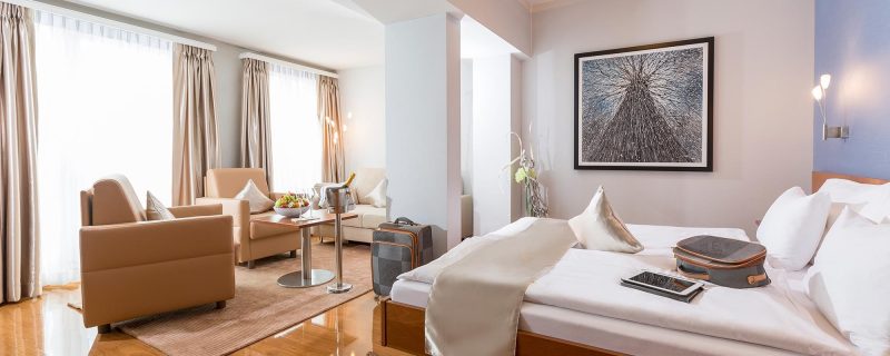 Elegante Junior Suite im Hotel Amaris mit komfortablem Bett und gemütlicher Sitzecke.