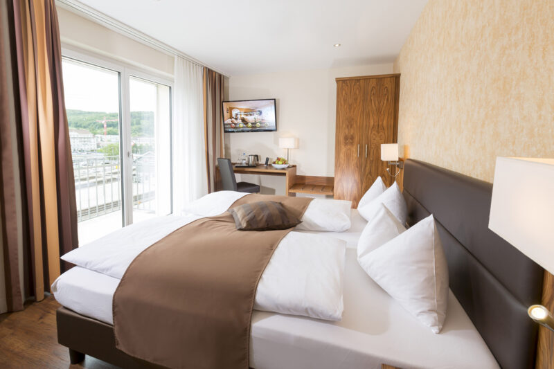 Komfortables Hotelzimmer im Hotel Amaris mit Doppelbett, Arbeitsplatz und Balkon mit Ausblick.
